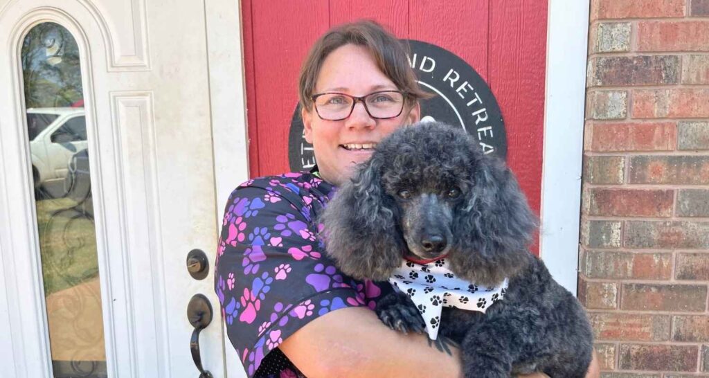 Woman holding a poodle outside the Buckaroos dog boarding facility