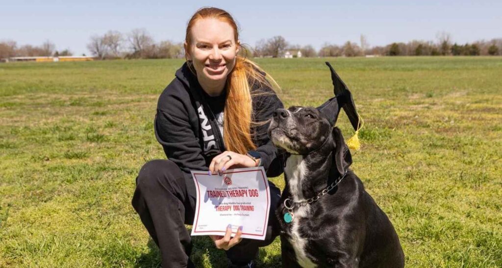 Handler and trained therapy dog with a graduation certificate at Buckaroos